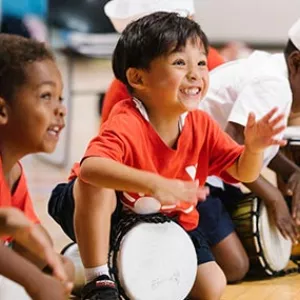 Boys smiling and playing drums at Bronx YMCA summer camp