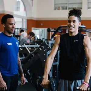 Teen lifts weights with personal trainer at Ridgewood YMCA strength training center in Queens