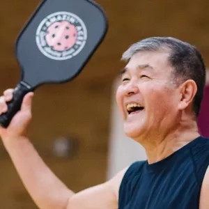Man smiling with pickleball paddle