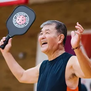 Man smiling with pickleball paddle