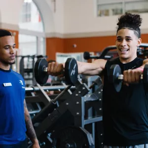 Man lifts weights with personal trainer