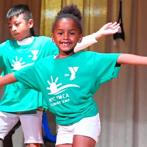 Kids in a dance and performance camp at the YMCA perform on stage.