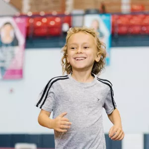 Boy running on track at Park Slope Armory YMCA kids run class in Brooklyn