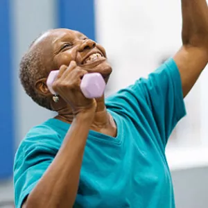 Woman lifting weights in YMCA chair yoga class for seniors.