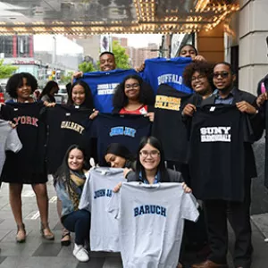 YMCA teens holding t-shirts of their selected college