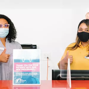 Two YMCA staff members in masks welcome visitors to the Y.
