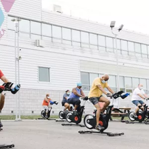 Participants on spin bikes in an outdoor fitness class at the YMCA.