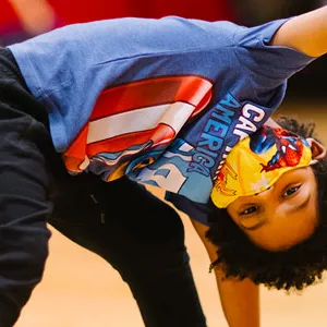 A boy wearing a mask doing a yoga pose at the YMCA.