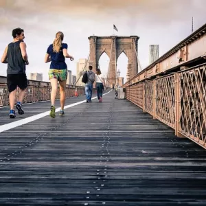 man and woman running on the Brooklyn Bridge