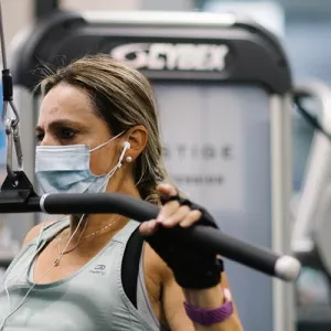 A woman in a mask works out on strength training equipment at the YMCA.