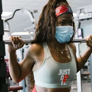 A woman in a mask works out at the YMCA.