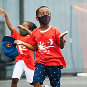 A boy in a mask running outside at YMCA Camp