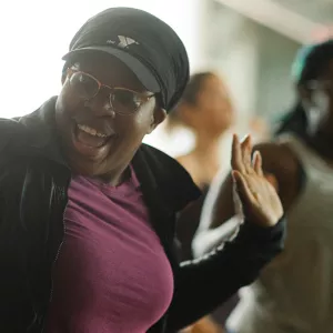 A woman in a Y hat in a group fitness dance class