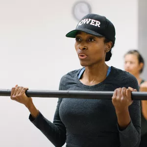 A woman lifting a bar in a group fitness class