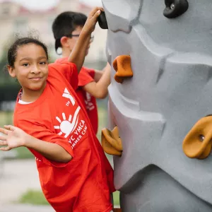 summer camp girl on climbing wall waving