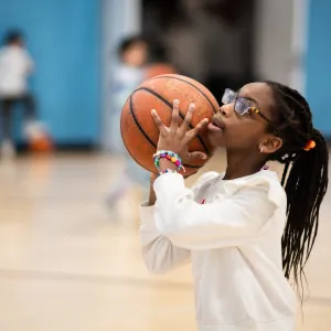 girl throws basketball in gym