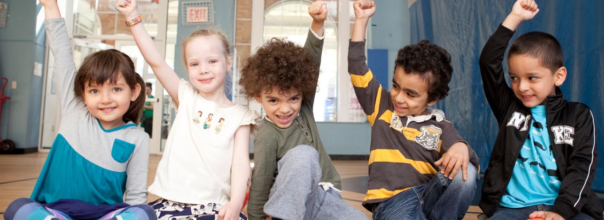 A diverse group of kids smile and raise their fists.