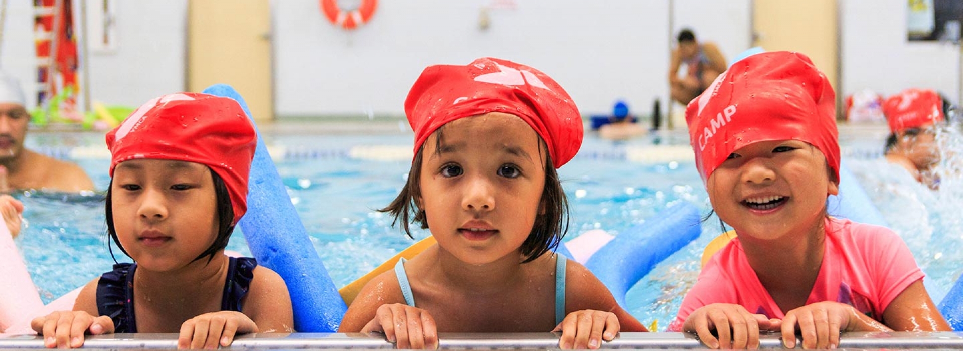 Three girls swimming in Long Island City YMCA pool during summer camp