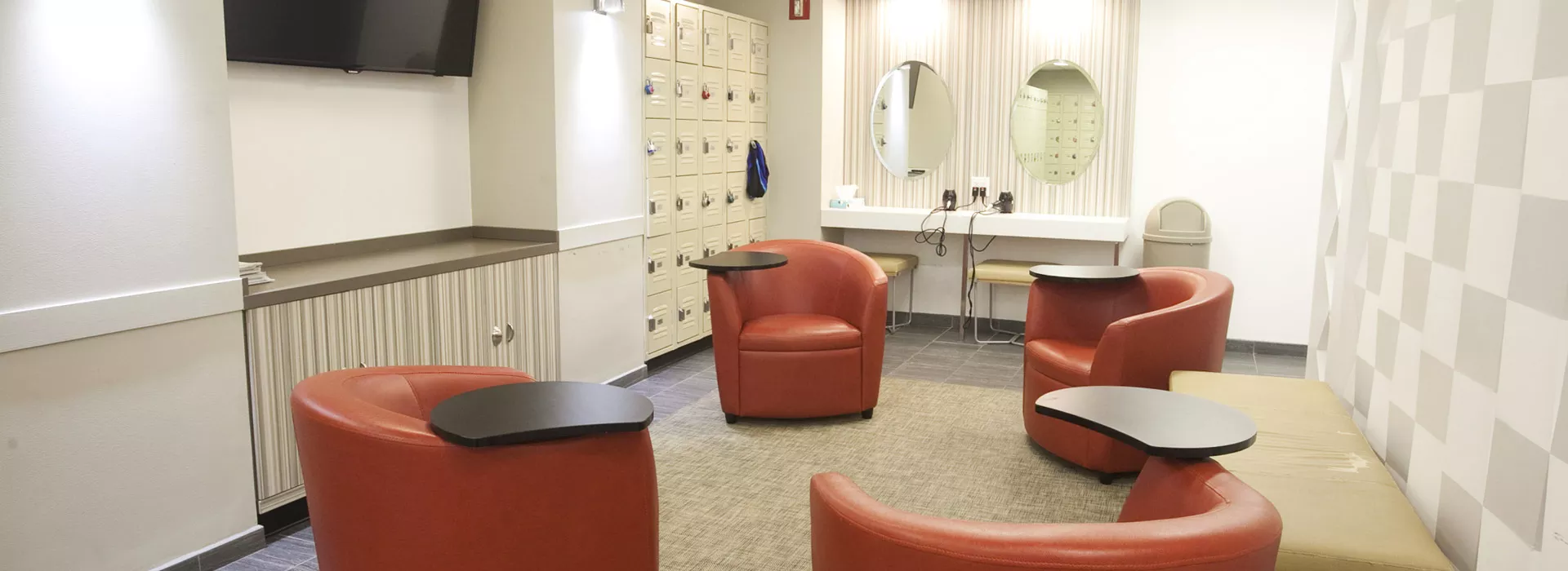 A clean, modern locker room with seating and mirrors at the Vanderbilt YMCA.