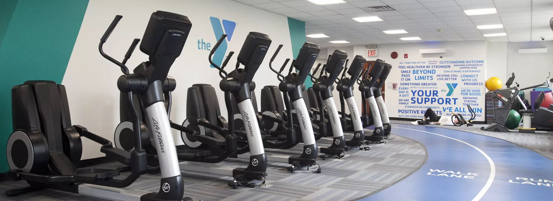An indoor track curves around a row of cardio equipment in the gym.