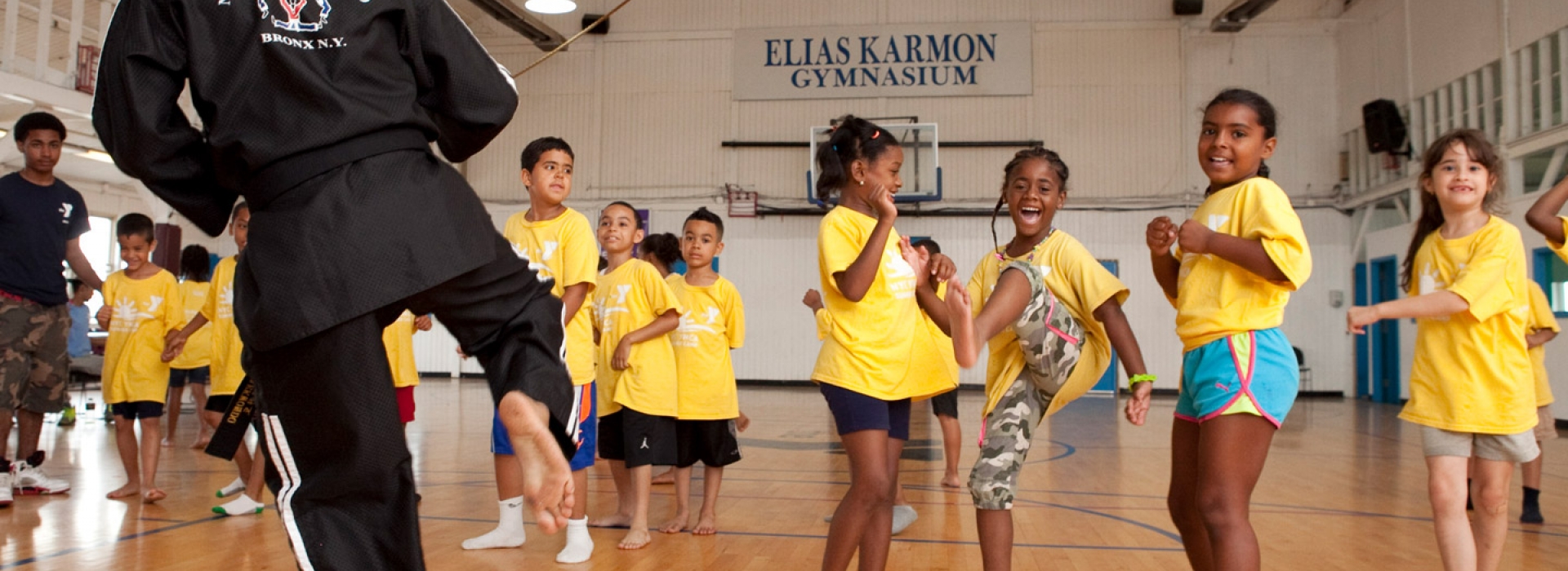 Kids doing martial arts in the gym, led by an instructor, at the Bronx YMCA Summer Day Camp.