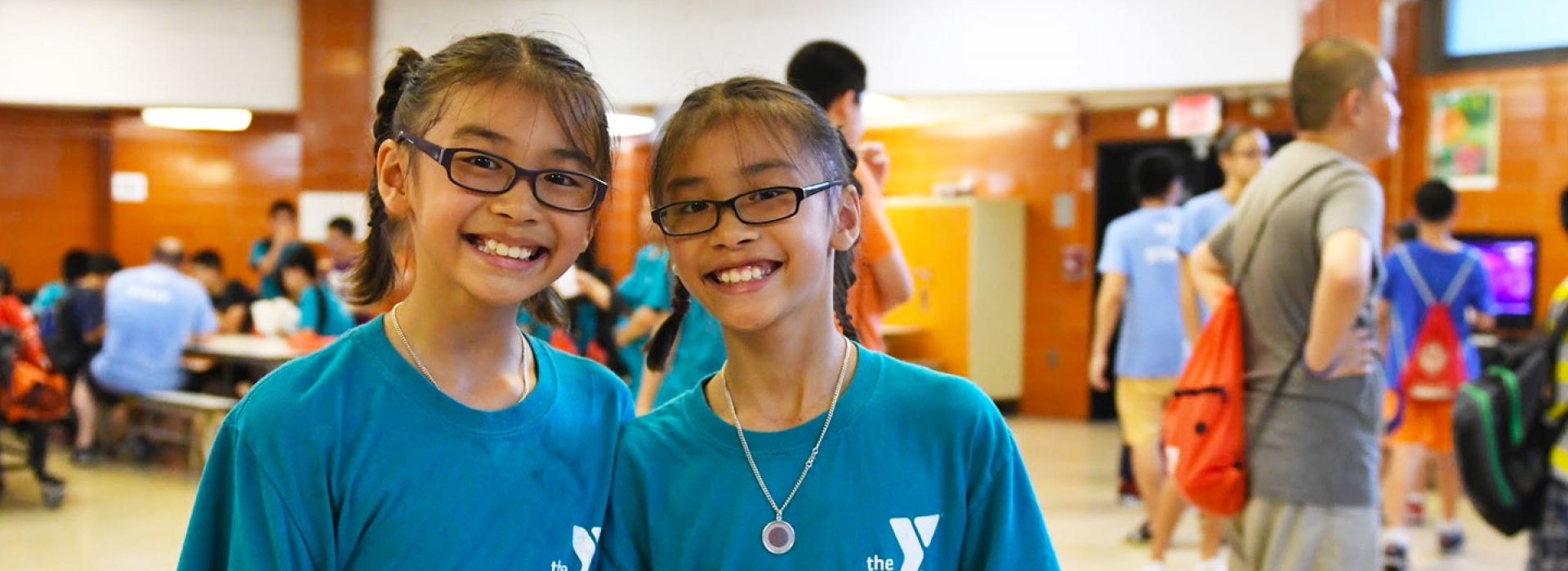 Two girls in glasses smile from the Chinatown YMCA Summer Day Camp.