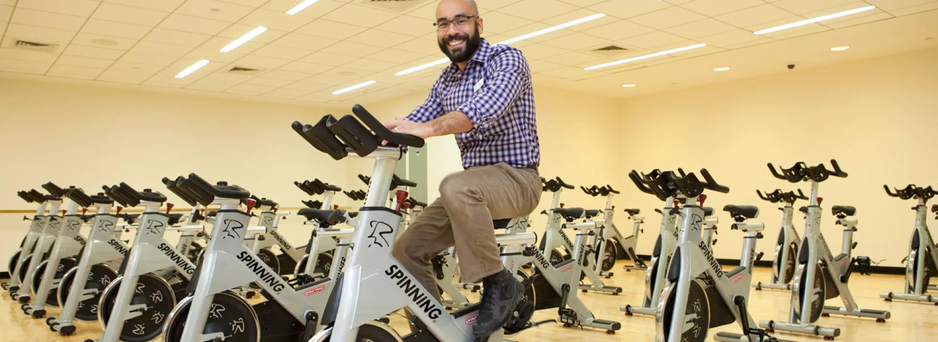 A man on a spin bike in a studio full of spin bikes at the Coney Island YMCA.