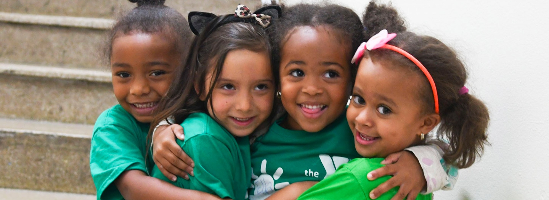 A diverse group of girls hugging each other at the Harlem YMCA summer day camp.