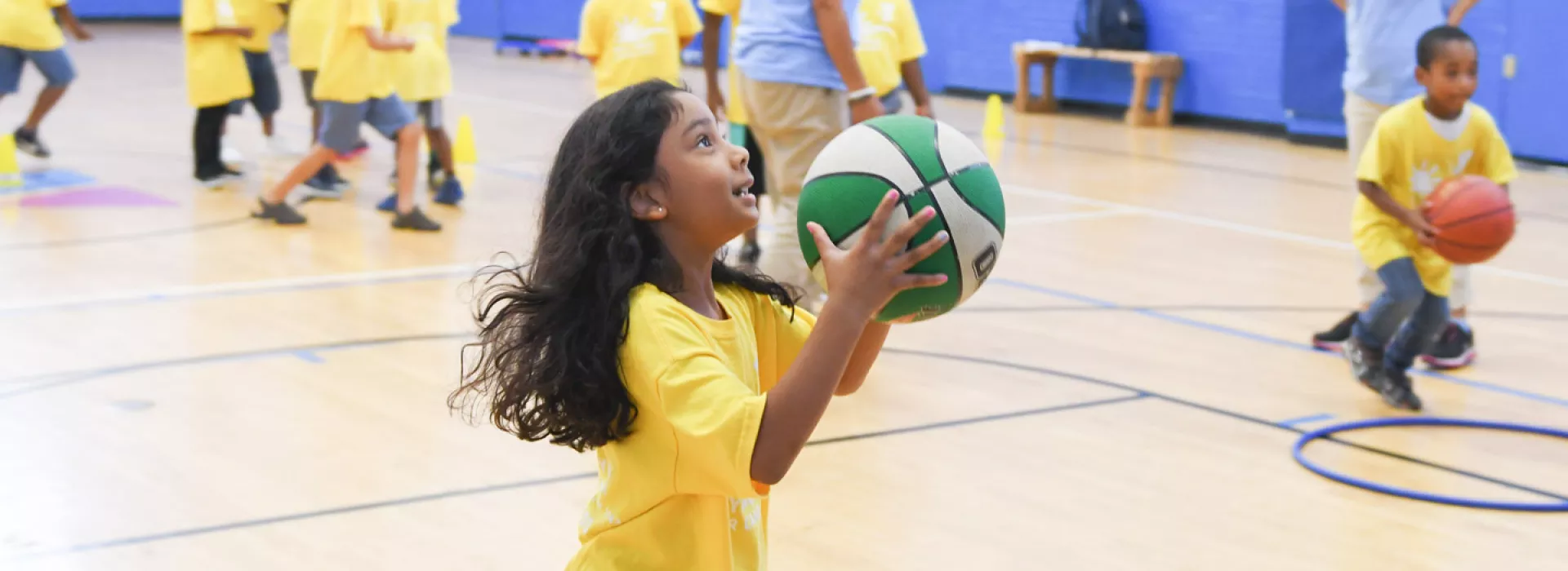 A young girl plays basketball in the Jamaica YMCA gymnasium.