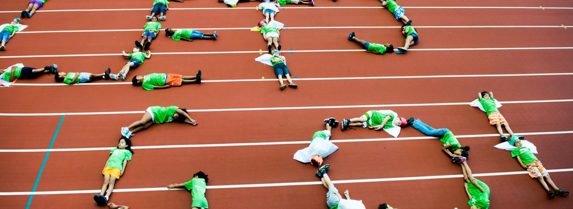 Kids form letters with their bodies on the track at the Prospect Park and Park Slope Armory YMCA summer day camp.