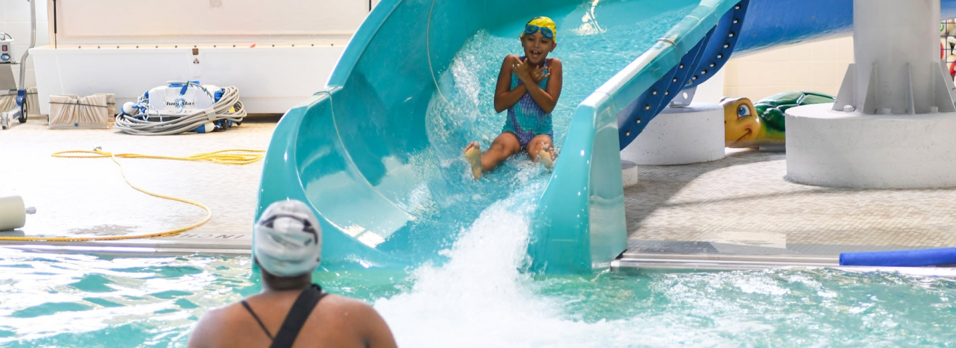 A camper slides down the water slide to a YMCA camp counselor.