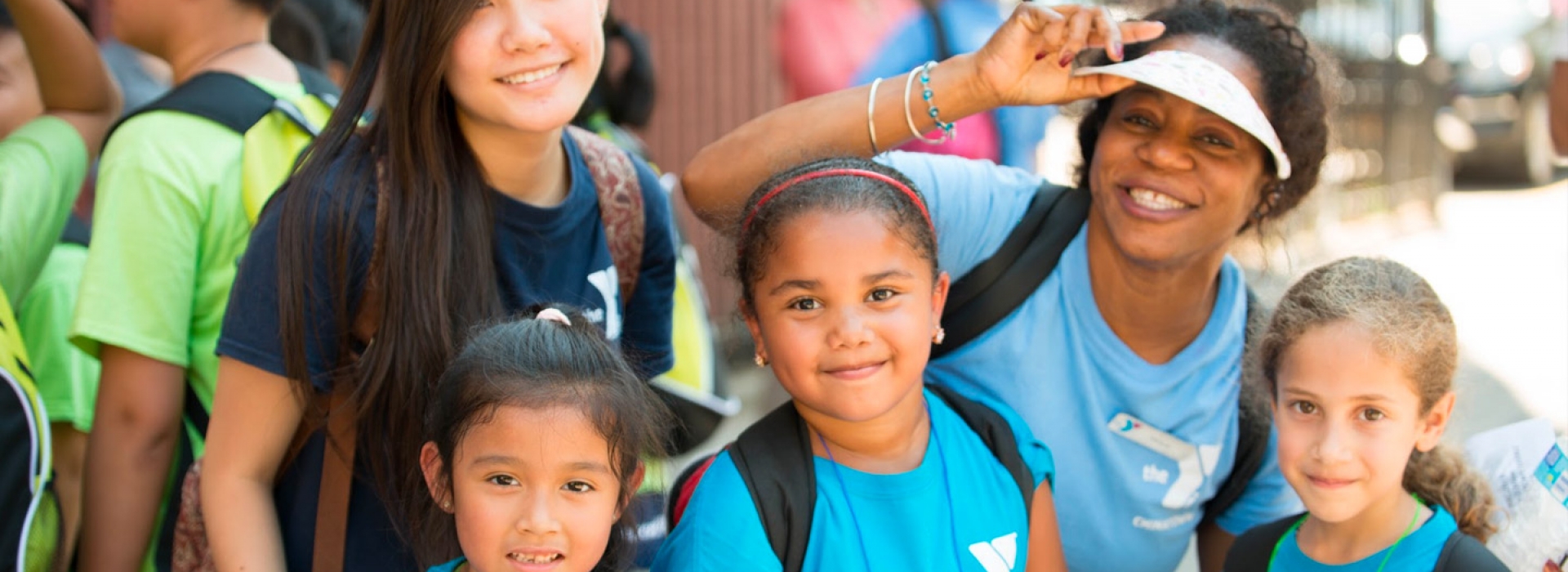 Three kids pose with YMCA camp counselors at the Chinatown YMCA summer day camp.