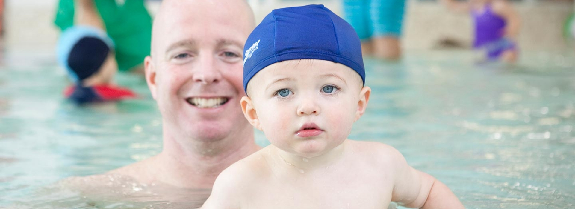 Dad and baby swimming in Rockaway YMCA indoor pool