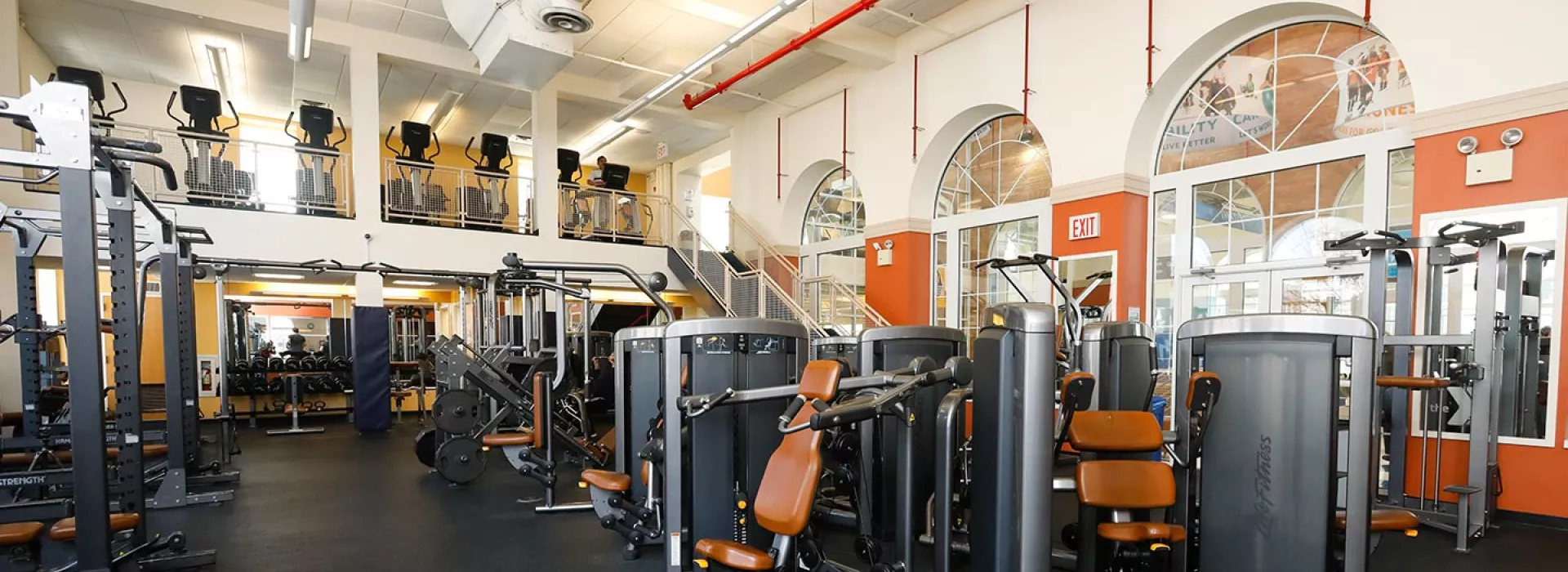 Weight room with strength training equipment at Ridgewood YMCA with view of upstairs ellipticals