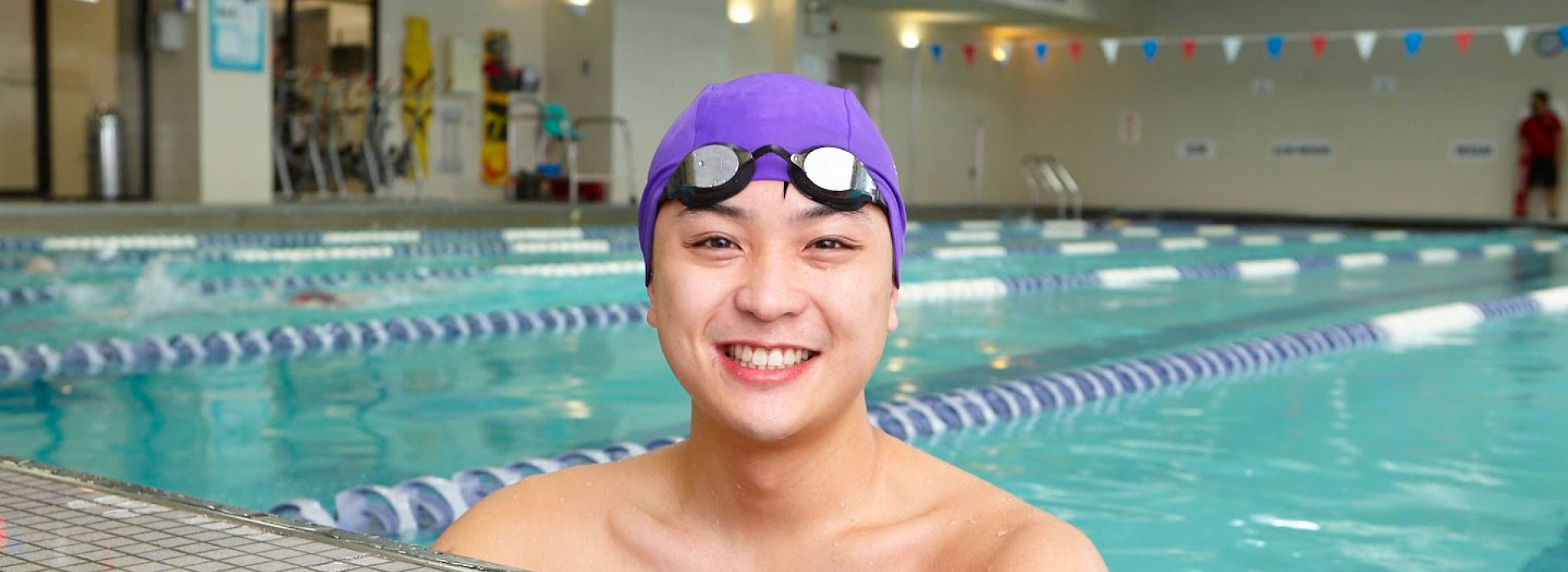 Man smiling at end of lap lane of Vanderbilt YMCA indoor pool