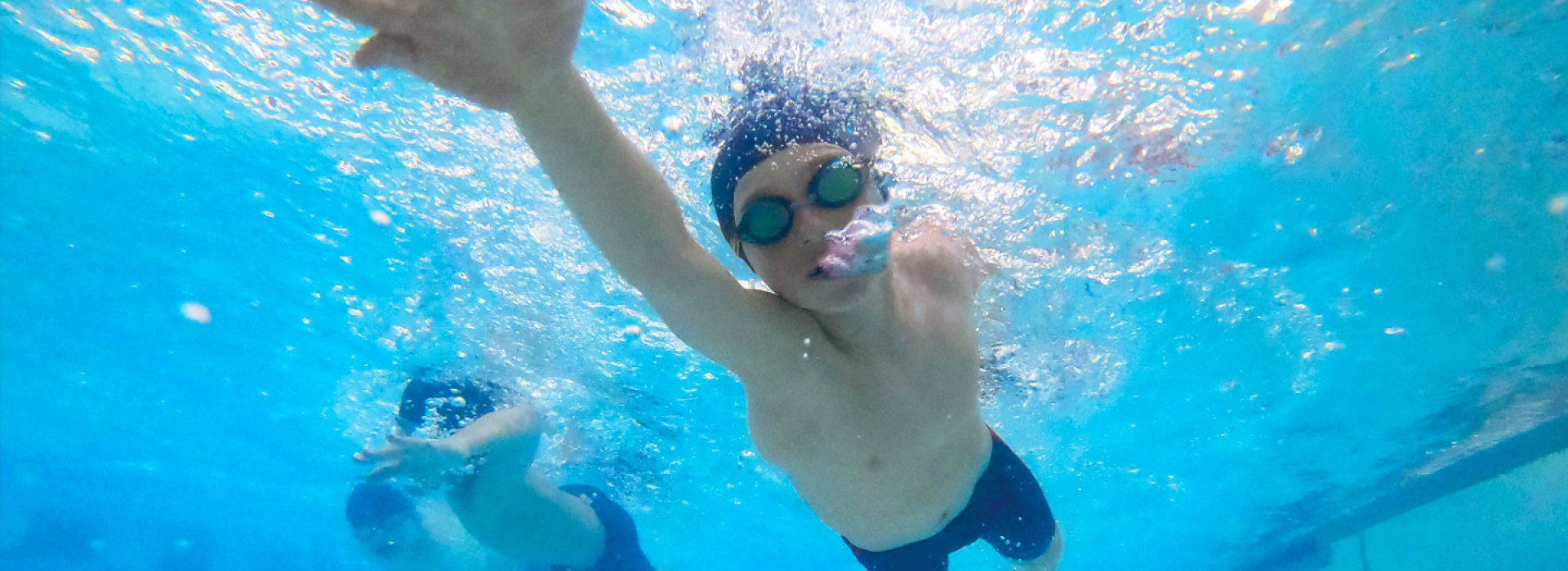 Boy swims laps at McBurney YMCA indoor pool with bubbles coming out of his face