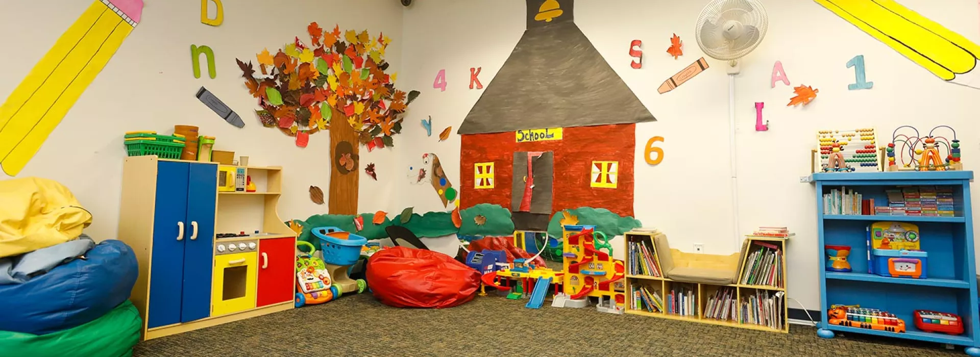 Playroom for children with toys, beanbags, wall decorations, and carpets