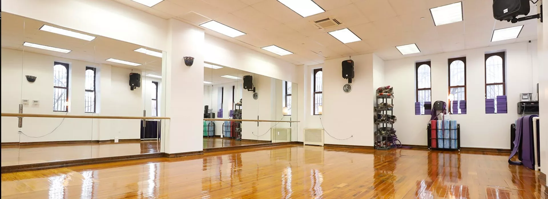 Group fitness studio with ballet barres, yoga mats, foam rollers at YMCA in Brooklyn