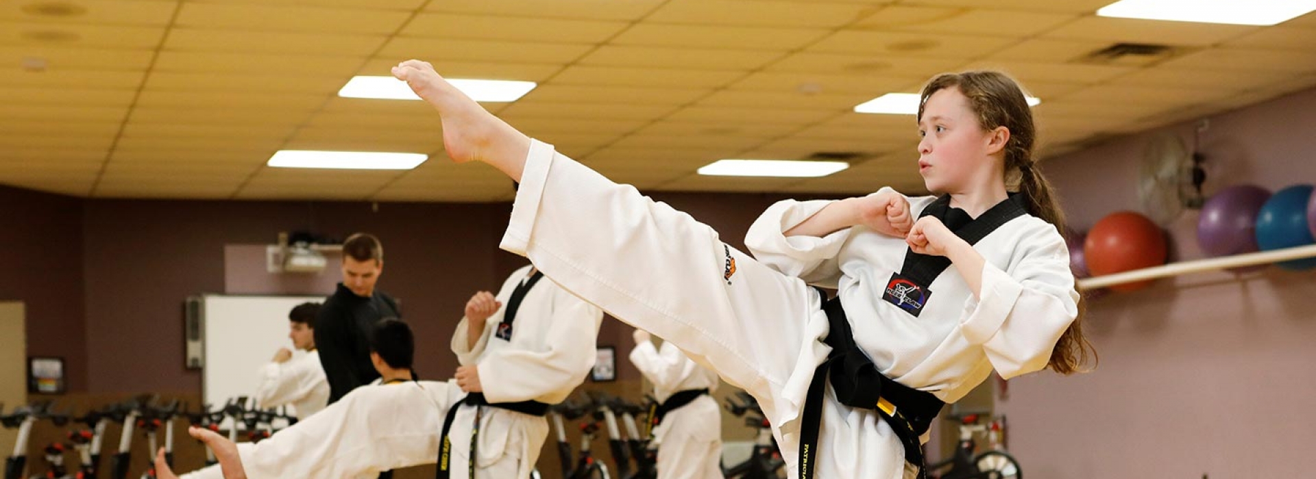 Girl doing high karate kick in YMCA martial arts studio in Staten Island