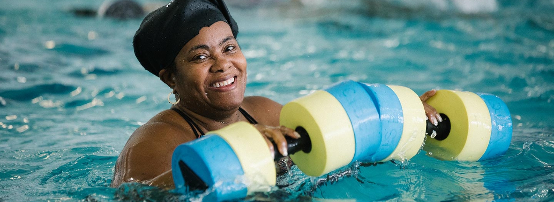 Woman with foam water weights during aqua aerobics class at Bronx YMCA indoor pool