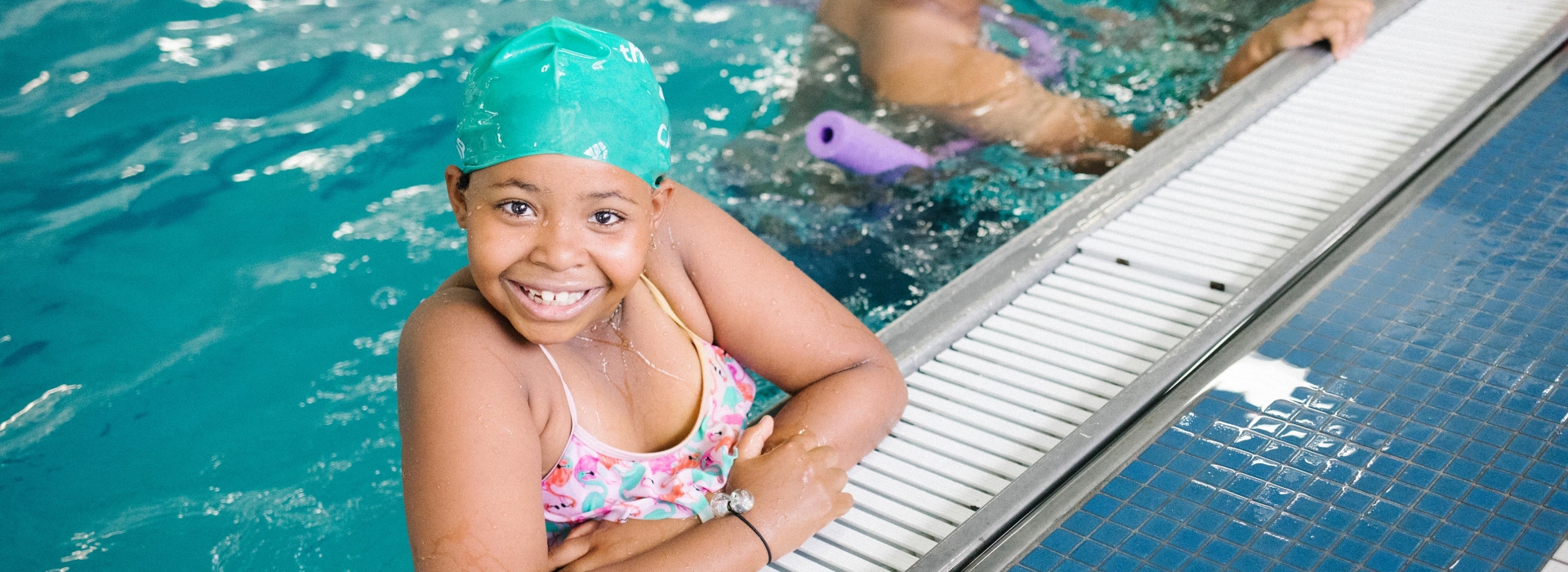 Girl smiles on side of Castle Hill YMCA indoor swimming pool