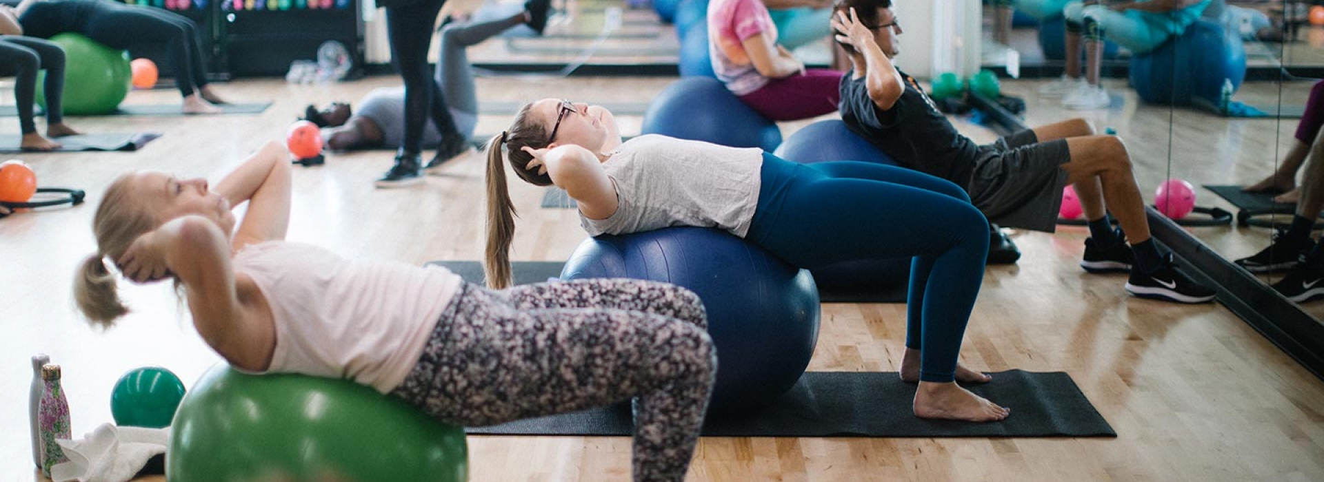 Workout class on yoga mats using balls to do core training exercises at Rockaway YMCA fitness studio