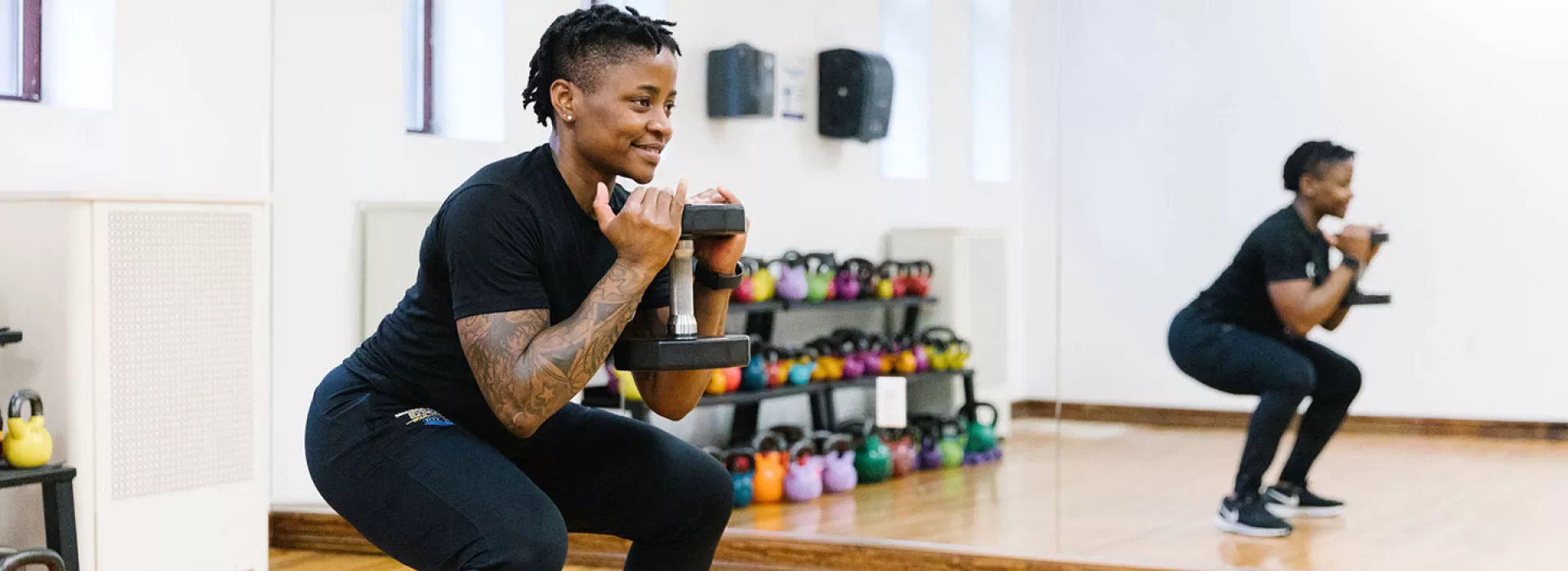YMCA instructor demonstrates squat with weights