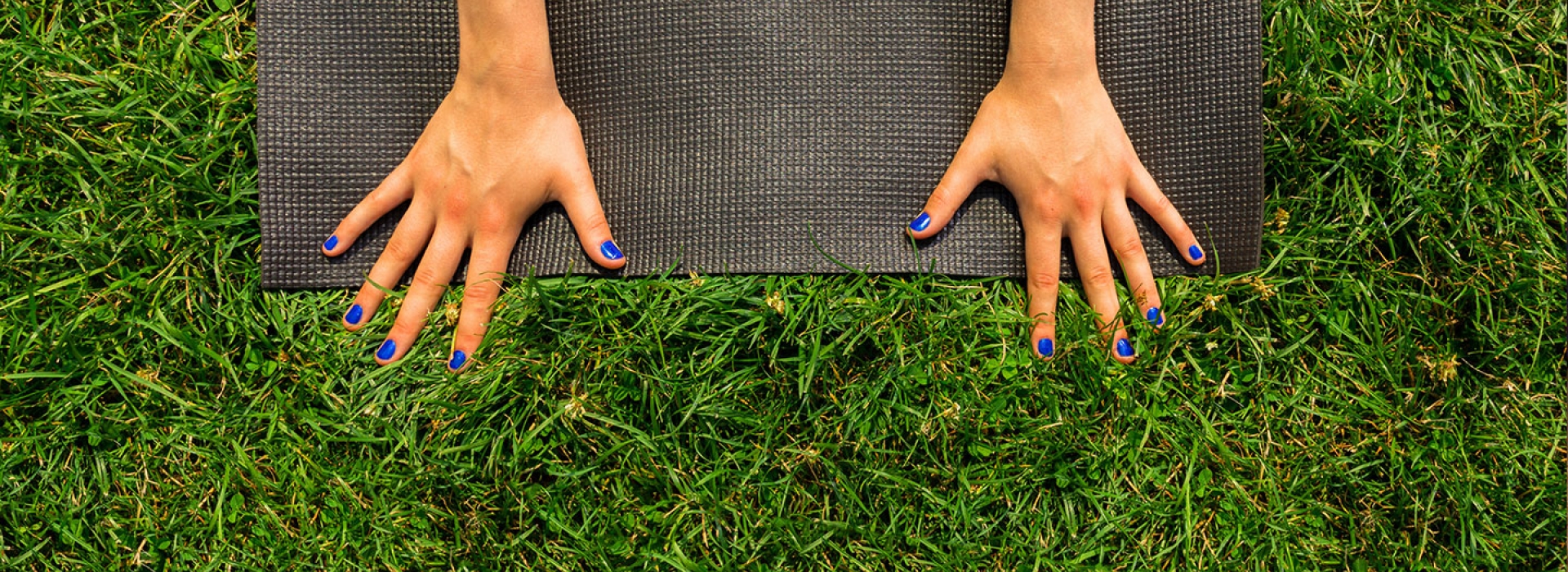 Hands on yoga mat in grass