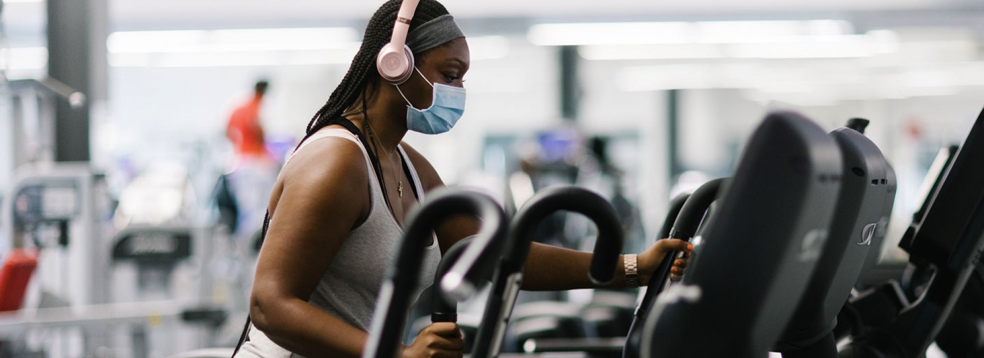 A YMCA member in a mask works out on an elliptical machine at the Y.