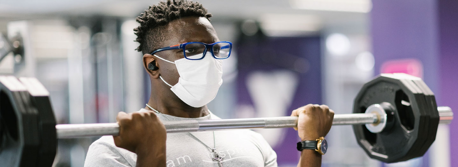 A YMCA member in a mask lifts weights.