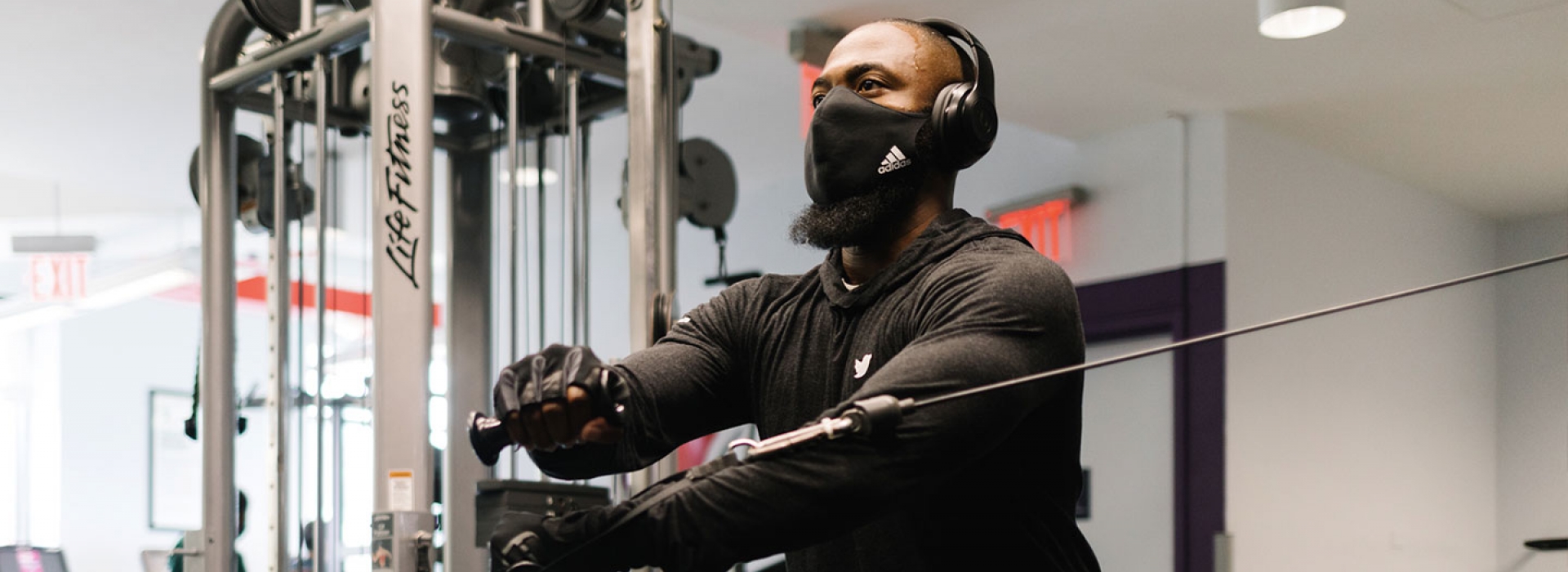 A YMCA participant in a mask works out on strength training equipment.