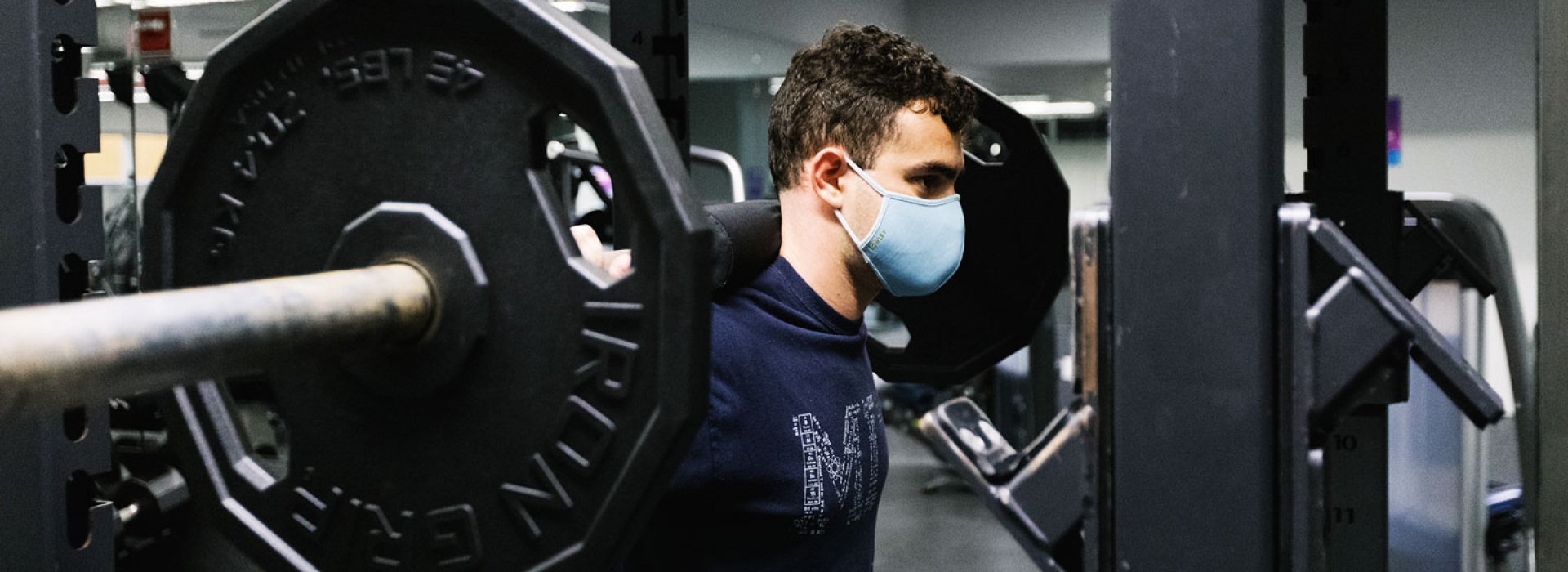 A YMCA member lifts weights while wearing a mask at the Y.