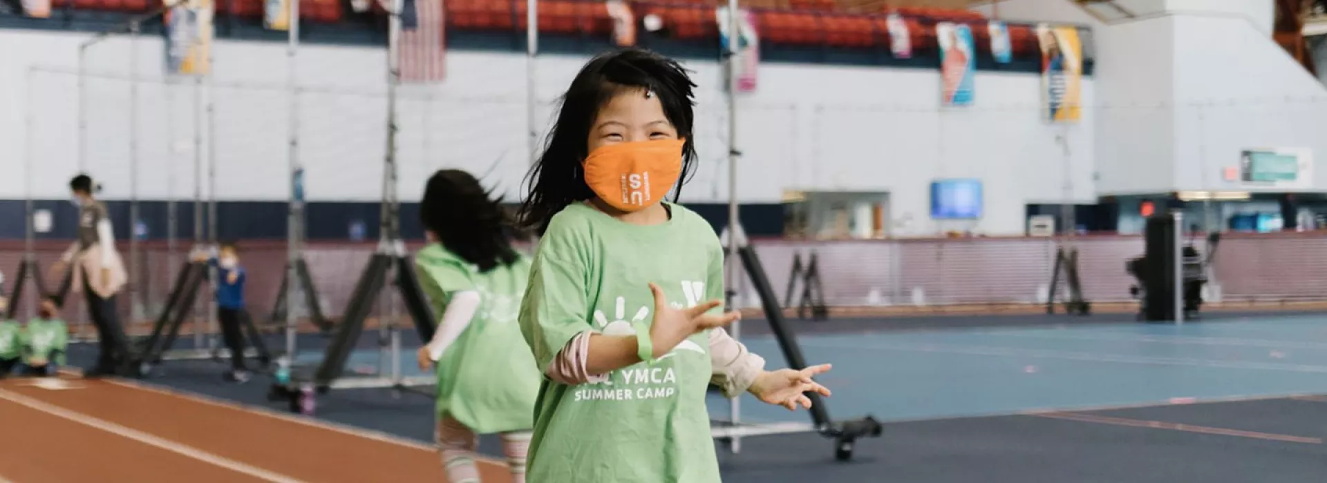 A girl wearing a mask smiles during camp at the YMCA.