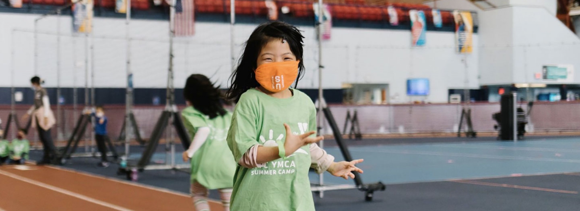 A girl wearing a mask smiles during camp at the YMCA.